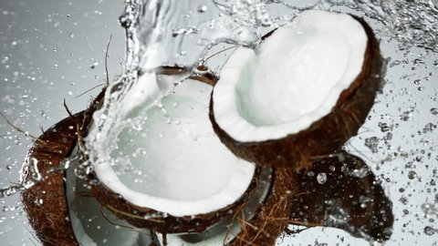 Super Slow Motion Shot of Flying Fresh Coconuts and Water Side Splash on Light Grey Background at 1000fps.