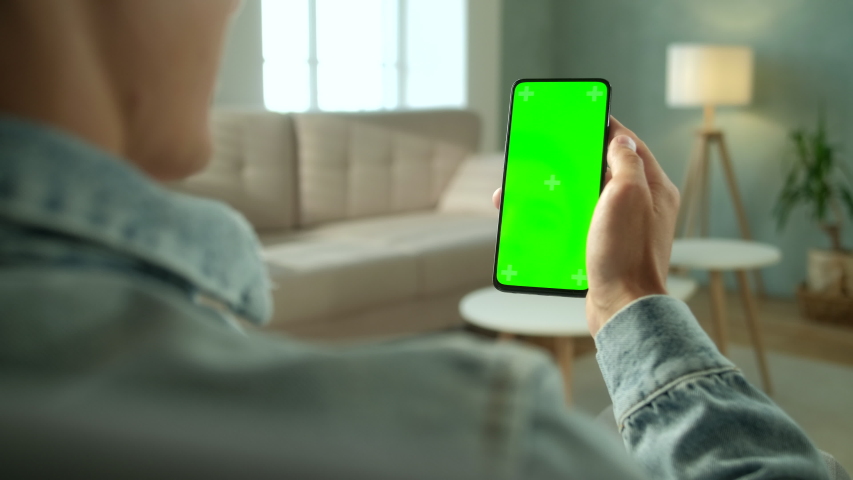 Back View of Brunette Man Holding Chroma Key Green Screen Smartphone Watching Content Without Touching or Swiping. Boy Using Mobile Phone, Browsing Internet, Watching Content, Videos, Blogs. Royalty-Free Stock Footage #1054870514