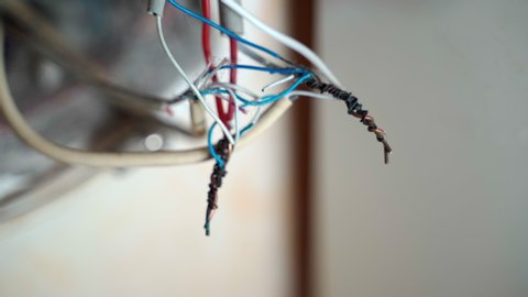 White, blue and red electrical wires twisted with black insulting tape, cables of power and energy in junction box inside the wall in residential building apartment. Engineering industry