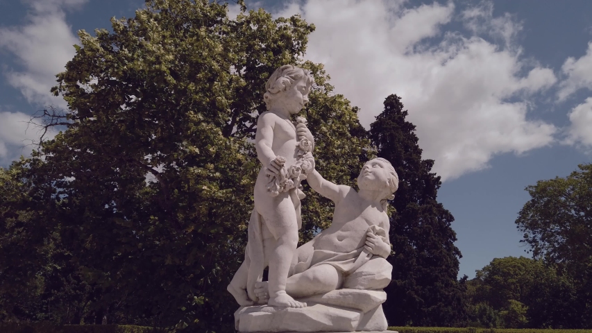 A marble statue with two kids in a garden.