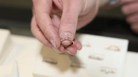 Jeweler Pointing Finger To A Gold Ring With Diamonds. Close up video as jeweler fingers holding golden ring.