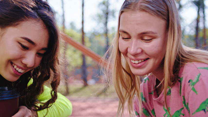 Beautiful ladies multiethnic enjoying the time together in the park closeup to the camera they watching something on the tablet. Shot on ARRI Alexa Mini
