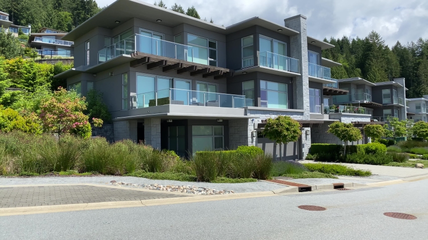 Establishing shot. Neighbourhood of luxury houses with street road, small green trees and nice landscape in Vancouver, Canada. Blue sky, white clouds. Day time on June 2020. Pan right. H.264. Royalty-Free Stock Footage #1054889600