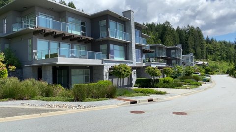 Establishing shot. Neighbourhood of luxury houses with street road, small green trees and nice landscape in Vancouver, Canada. Blue sky, white clouds. Day time on June 2020. Pan right. H.264.
