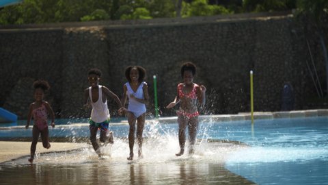 Group of happy African American children enjoy running by the pool. Family Boy and girl Summer water play activities during holiday  the long weekend. Concept of living together