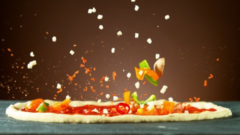 Super slow motion of falling pizza ingredients on yeast dough. Filmed on high speed cinema camera, 1000 fps.