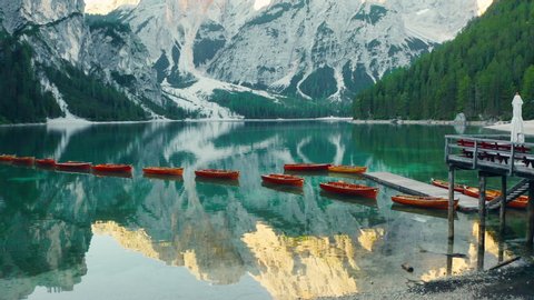 Flying out over the calm emerald green waters of Lake Braies, revealing the Prags Dolomites, aerial