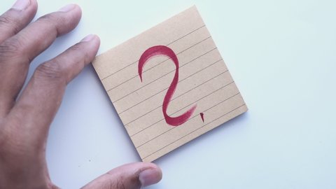 Man hand in red marker writing question mark on notepad