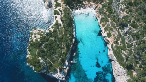 Stunning top down aerial shot of a beautiful bay in paradise with incredible clear and turquoise water in the Mediterranean Sea in Mallorca, Spain - 4k Footage of Balearic Island.