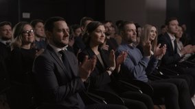 Large group of people applauds to welcoming speech at business conference or economy forum. Stage talk at summit meeting in crowded hall. Attractive 30s man clapping hands at modern event slow motion - Powered by Shutterstock - Get 15% off with code: PIKWIZARD15