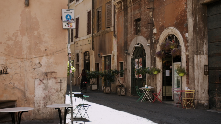 4K. Streets of Rome symbol of Dolce vita. historic buildings in pastel colors. brunette girl rides fast through the narrow streets of Trastevere. Medium close on 4k Blackmagic Cinema camera. BMPCC4K