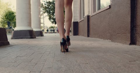 Following Shot of Silhouette of Female Legs in High Heels Shoes Walking Along Dark Hallway. Slow Motion. Beautiful Scene of Woman Walking Gracefully.