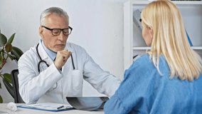 middle aged doctor talking with patient and looking at x-ray