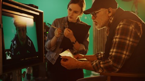 Director Looks at Display and Compares to Storyboard while Shooting Blockbuster Movie. Green Screen Scene with Actor Wearing Motion Caption Suit. On Film Studio Set Professional Crew Shooting Movie