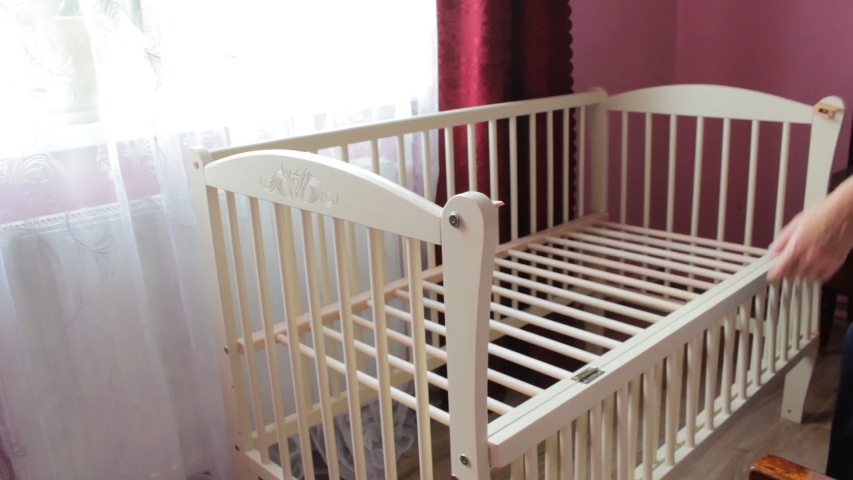 man puts the mattress in the cradle,the father folded the cradle for the baby and puts a new mattress Royalty-Free Stock Footage #1054910573