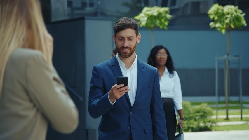 Handsome successful young man bearded entrepeneur walking with smartphone on office break nearby corporate building. Ambitious people. Employment.