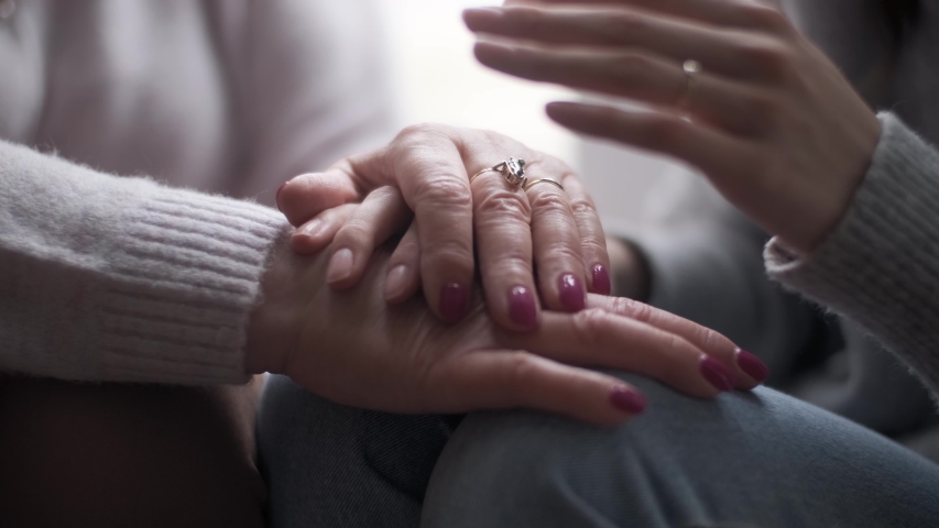 Young adult woman daughter holds elderly mother by the hand. Helping old people, supporting in difficulties, mutual assistance concept. | Shutterstock HD Video #1054912796