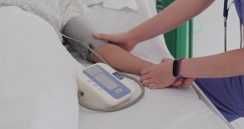 The doctor measures blood pressure in the senior patient hand.