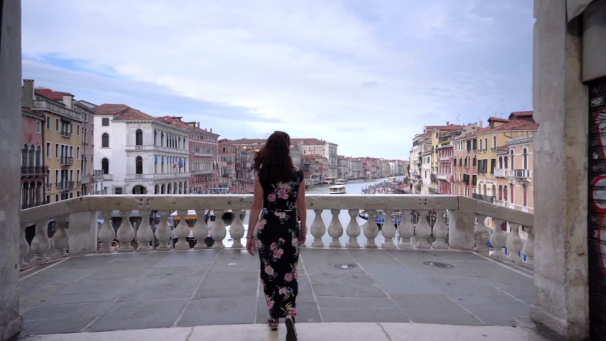 Attractive young woman walk on the bridge of Rialto in Venice Italy looking at the Grand Canal | Shutterstock HD Video #1054918931