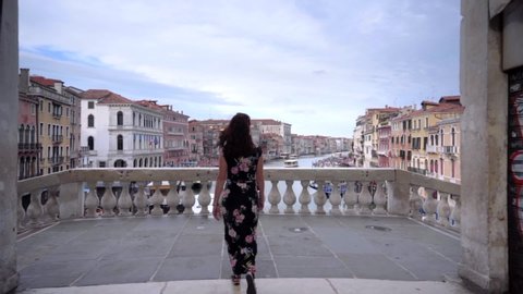 Attractive young woman walk on the bridge of Rialto in Venice Italy looking at the Grand Canal