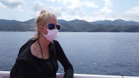 Woman on ferry boat with a surgical mask during Covid-19. Italian tourist woman travels on Tyrrhenian Sea to Elba Island by ferry boat. Coronavirus quarantine holiday travel in COVID pandemic in Italy