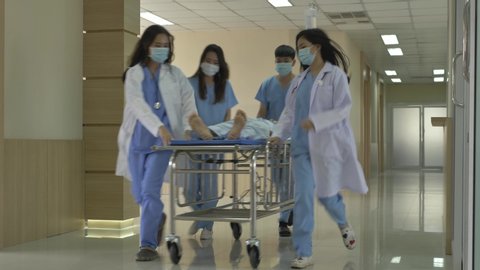 Hospital emergency department team carrying a stretcher with the patient through the hospital hall.
