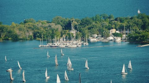 View of the Central Island in front of the city of Toronto. Green trees and many sailing yachts near it