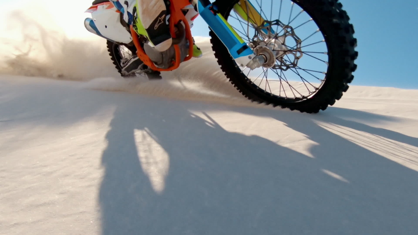 POV shot of professional dirt bikers riding on a motorcycle. Dirt bikers in action driving the motorbike in desert. Motocross bike rider over sand dunes.
