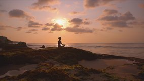 Silhouette of young woman relaxing and enjoy beauty sunset on the ocean coast. Girl doing yoga on the beach. Person meditate outdoor and enjoy orange sunlight. Concept of fitness, health, relax, yoga. - Powered by Shutterstock - Get 15% off with code: PIKWIZARD15