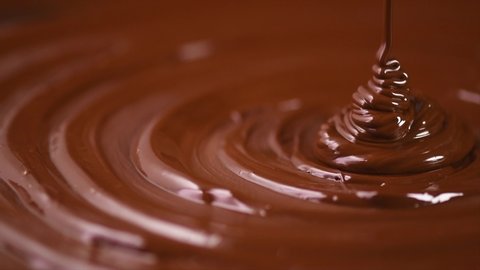 Chocolate. Pouring melted liquid premium dark chocolate. Close up of molten liquid hot chocolate swirl. Confectionery. Confectioner prepares dessert, icing. 4K UHD video, slow motion