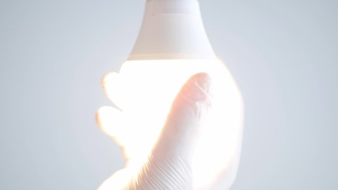 Electrician's Hand Rotates a Led Bulb in Electrical Socket Turning Off the Light