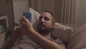 Man lying down on couch while looking at his cell phone alone at night - Powered by Shutterstock - Get 15% off with code: PIKWIZARD15