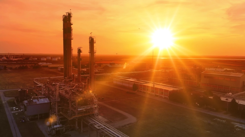 Aerial view of petrochemical plant at sunset. Drone shot flying over facility, flock of birds in sky at beautiful day