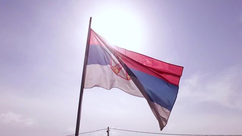 Flag of Serbia fluttering in the wind with clear sky background.