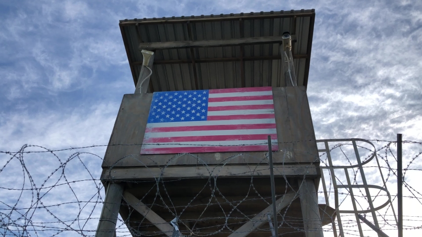 barb-wired view protected fence on low angle and blue sky as pickup shot for protected army base area or confinement military or secured facility protection barrier. Low sun at dusk and no people. Royalty-Free Stock Footage #1054938242