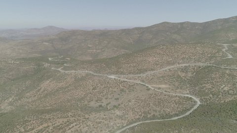 At the US_Mexico border, aerial shot of mountains on US side and a convoy off in the distance in stunning 4K60.  Notorious drug smuggling and human trafficking location