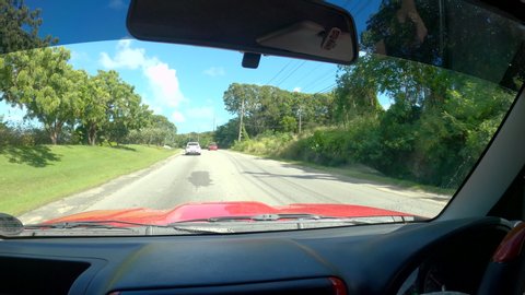 BRIDGETOWN, BARBADOS, CARIBBEAN ISLANDS, DECEMBER 2019: POV: Driving down the scenic outskirts of Bridgetown on a sunny day. Fellow tourist drives you along an asphalt road running across Barbados.
