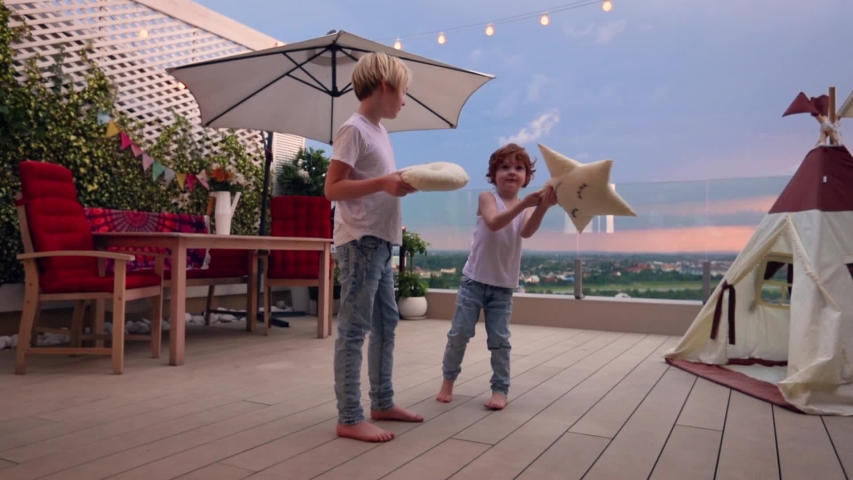 cute kids having fun, playing and fighting on rooftop patio during the sunset
