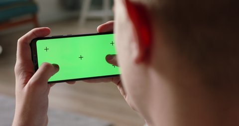 Close up shot of man playing video games on his smart phone with chroma key green screen, quickly tapping on display - connection, technology concept 4k video template