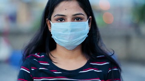 Young Asian/ Indian woman wearing surgical face mask to protect herself from harmful viruses and pollution. person protecting herself from air contamination or corona virus or covid-19 by wearing mask
