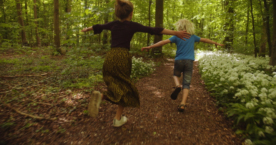 Shot of little carefree children happily running along the forest path with both their arms stretched wide open