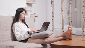 The beautiful woman lying on the sofa is using the computer.