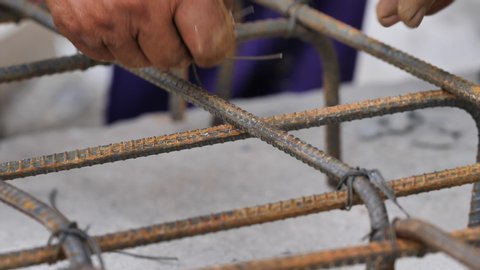 Closeup shot of bar bender hands fixing steel reinforcement bars with binding wire