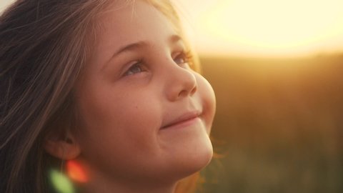 happy little girl child looking up eyes dreams. kid wants a dream come true portrait at sunset. baby daughter look up silhouette dreaming of a happy childhood. free face sister side view thinks