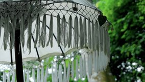 Video of an old white decorated fabric umbrella from the sun standing in the forest