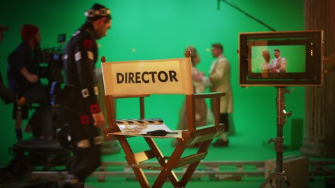 On Film Studio Set Focus on Empty Director's Chair. In the Background Professional Crew Shooting Historic Movie, Cameraman on Railway Trolley Shooting Green Screen Scene with Actors for History Movie