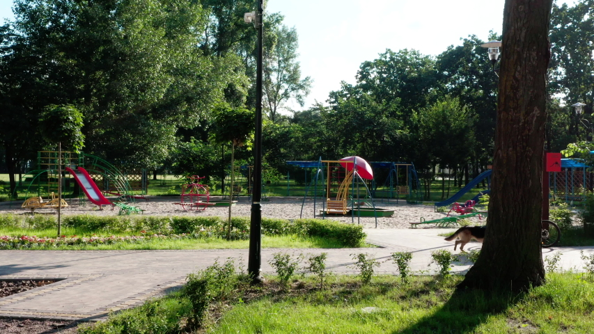 Aerial view. Playground with swings outside in a city park on a summer morning. Children playground among green trees and grass. Family holiday