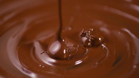 Chocolate. Pouring melted liquid premium dark chocolate. Close up of molten liquid hot chocolate swirl. Confectionery. Confectioner prepares dessert, icing. 4K UHD video, slow motion. 