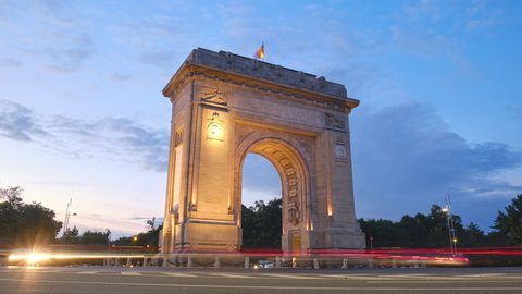 Arch of Triumph in Bucharest, Romania. Day to night looping hyperlapse in the evening, at blue hour, with car lights trails. City life, urban scene, transport, cityscape, sightseeing, travel concept.