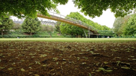Paris, France-06-12-2020: A spring time lapse view of the paris reuilly paul pernin garden and bridge with trees, leaf and people walking 
